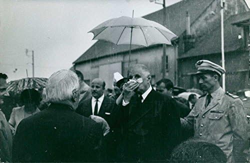 Foto vintage de Charles de Gaulle em pé com outras pessoas na chuva.